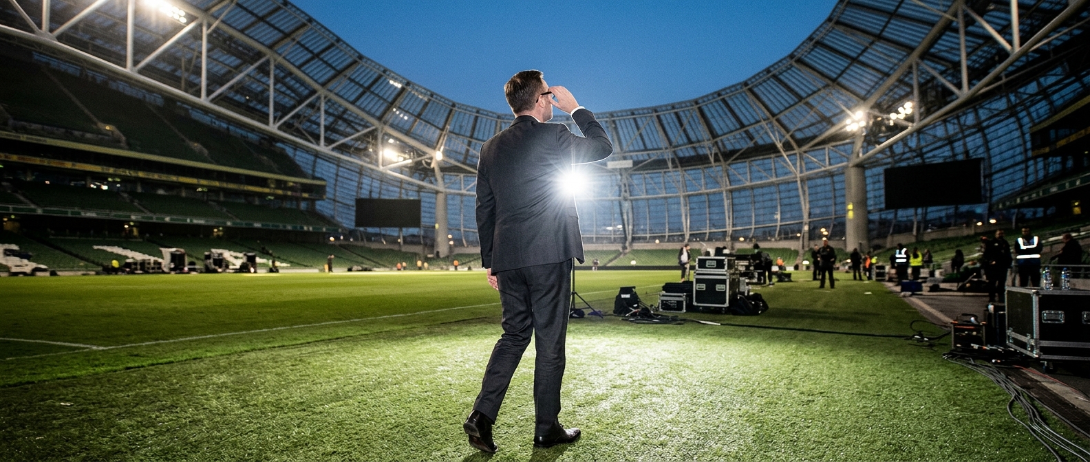 Venue executive standing on the pitch inside Dunedin's Forsyth Barr Stadium under evening floodlights — Phil King Takes th…