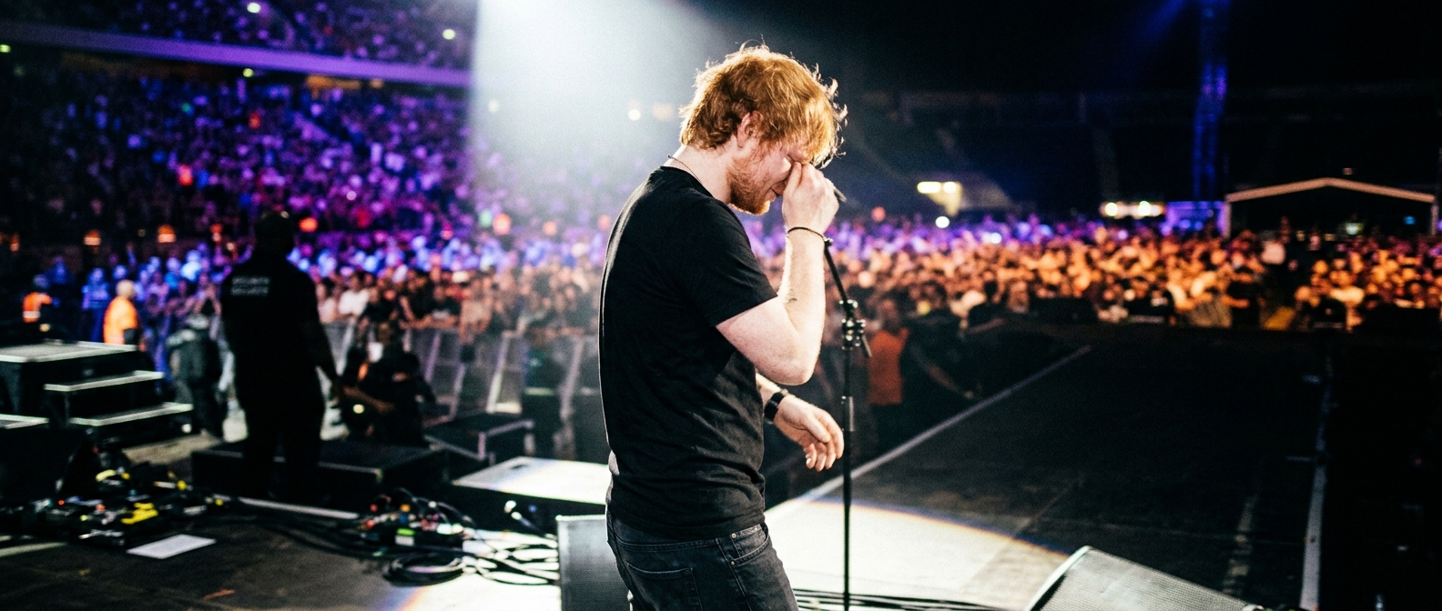 Ed Sheeran turns away from the microphone on stage at his Philadelphia concert amid tour controversy.